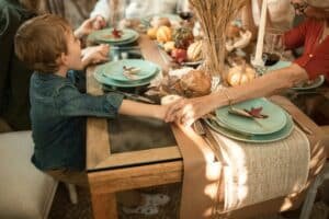 a boy holds hands with a grandma at the dining table before a meal