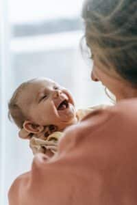 a woman holds an infant that is smiling